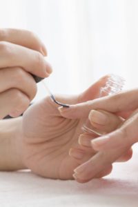 Frau trägt Nagelpföege auf