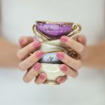 Beautiful woman hands with perfect pink nail polish holding little vintage tea cups, romantic shabby chic mood, can be used as background